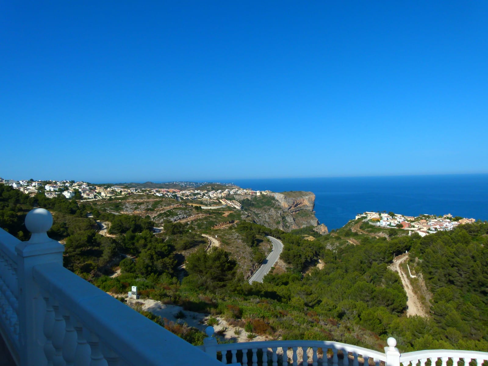 Vistas panorámicas desde la terraza con barandilla blanca hacia la costa y el mar azul.
