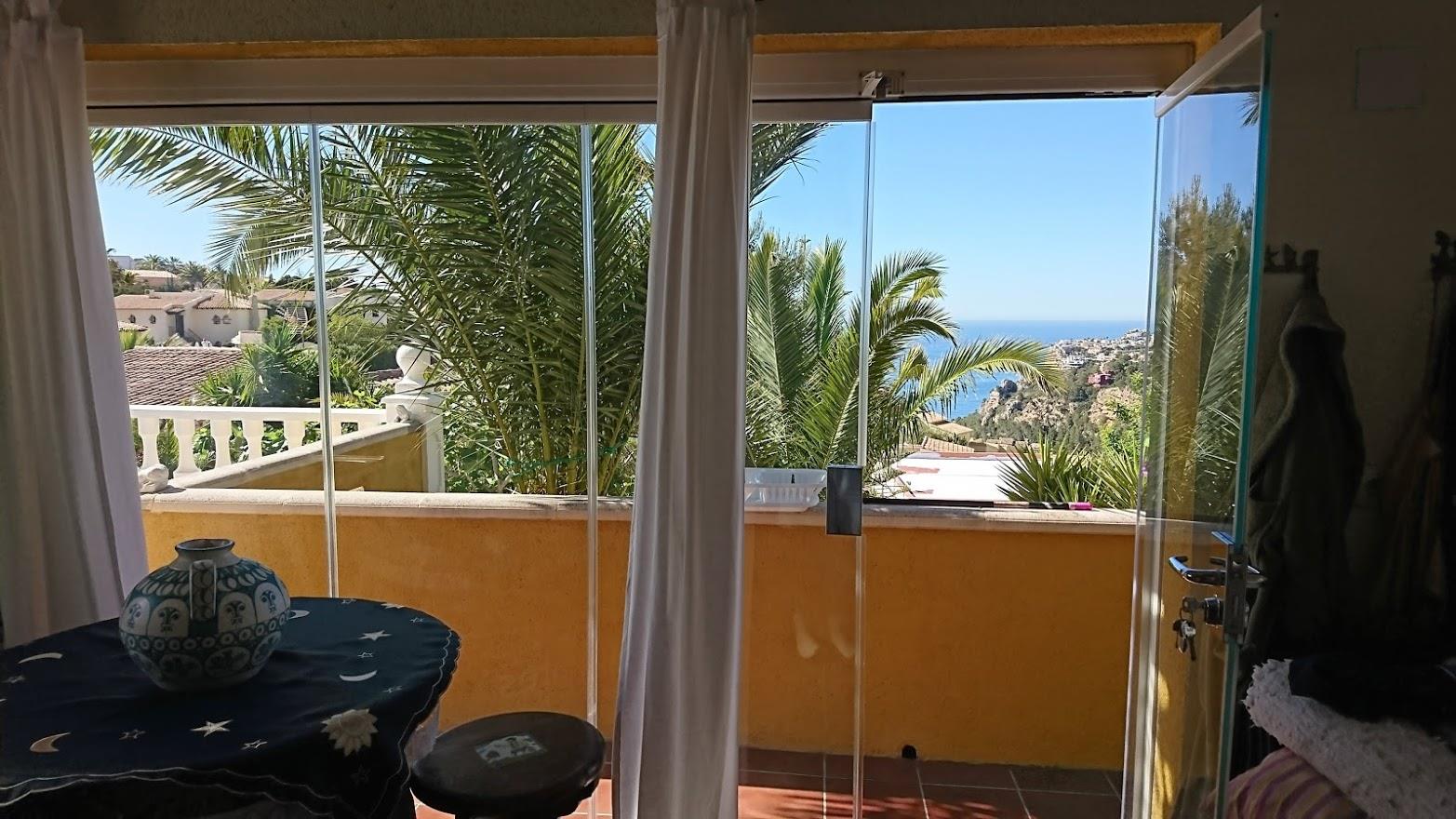 Naya acristalada con cortinas de cristal que ofrece vistas panorámicas al mar Mediterráneo y al jardín de palmeras. Espacio luminoso con suelos cerámicos.