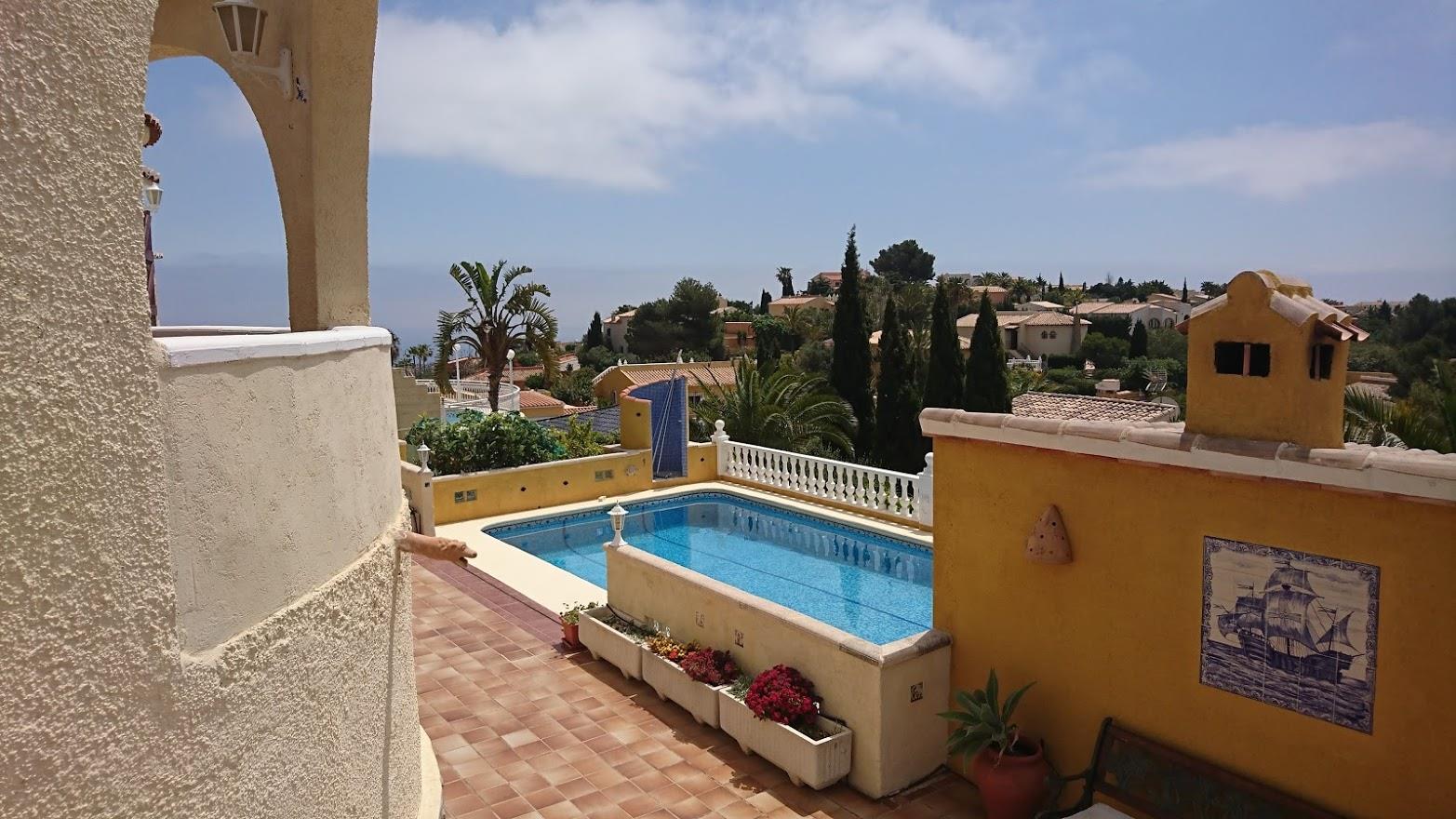 Terraza con suelos de terracota y vistas al mar, destacando la piscina rectangular y muros en tonos ocres con detalles cerámicos tradicionales.