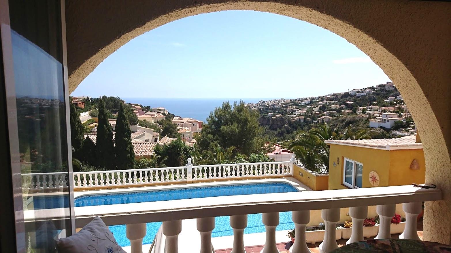 Vista desde la naya enmarcada por un arco mediterráneo, con vistas a la piscina privada, la balustrada blanca y el mar Mediterráneo.