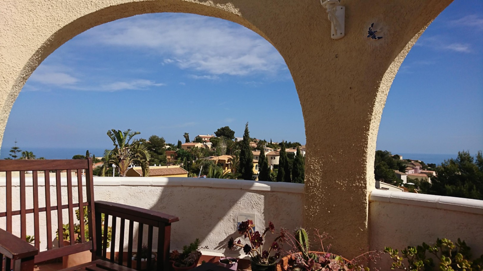 Vista panorámica al mar Mediterráneo desde la naya con arcos tradicionales, mobiliario de madera y plantas ornamentales en macetas.