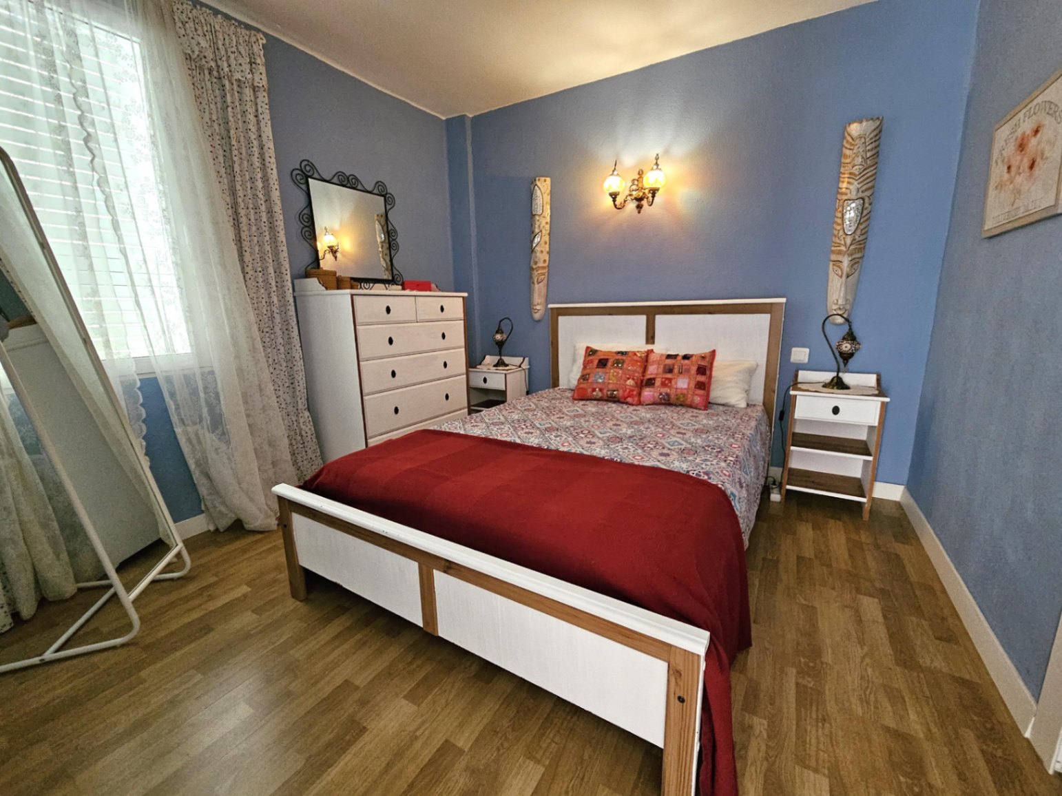 Dormitorio de diseño contemporáneo con paredes azules, suelos de parqué y mobiliario blanco. Dispone de cama doble, cómoda y abundante luz natural.