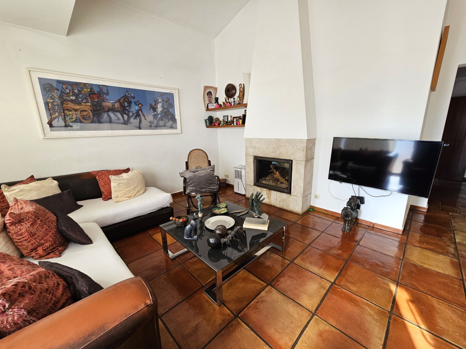 Salón con suelos de barro hechos a mano, chimenea de piedra integrada y techos altos. Dispone de mobiliario contemporáneo y una zona de estar con abundante luz natural.