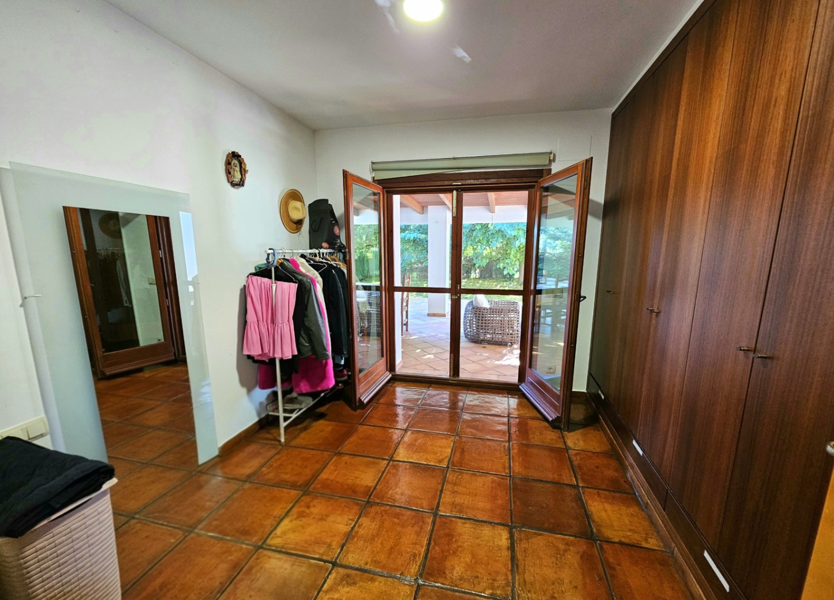 Vestidor con amplios armarios empotrados de madera, suelos de barro hechos a mano y acceso directo a la naya exterior a través de puertas acristaladas.