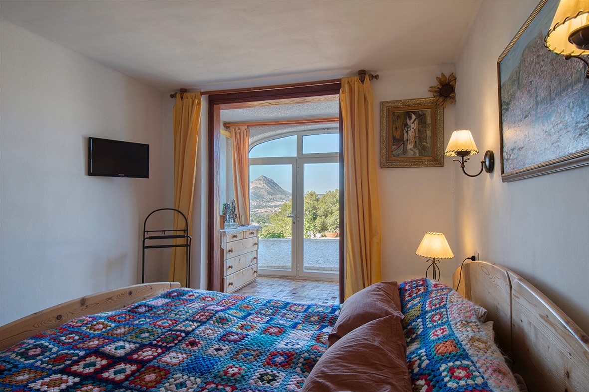Dormitorio de estilo rústico con mobiliario de madera y acceso directo a una terraza con vistas despejadas a la montaña y el entorno natural.