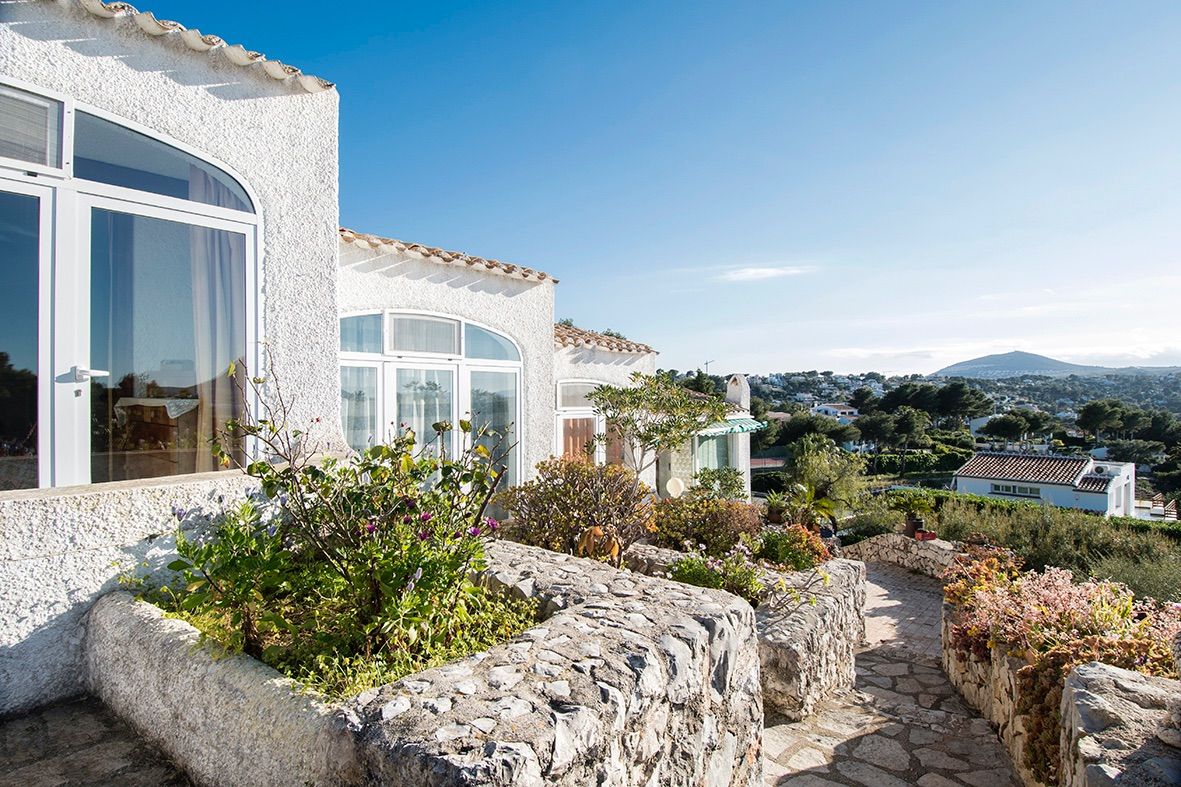 Fachada exterior de estilo tradicional con muros de piedra natural, ventanas de arco y vistas despejadas al valle del Portichol bajo un cielo despejado.