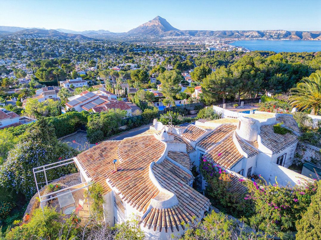 Vista aérea de la villa tradicional con tejados de teja curva, destacando las vistas panorámicas al Montgó y la bahía de Jávea desde su ubicación elevada.