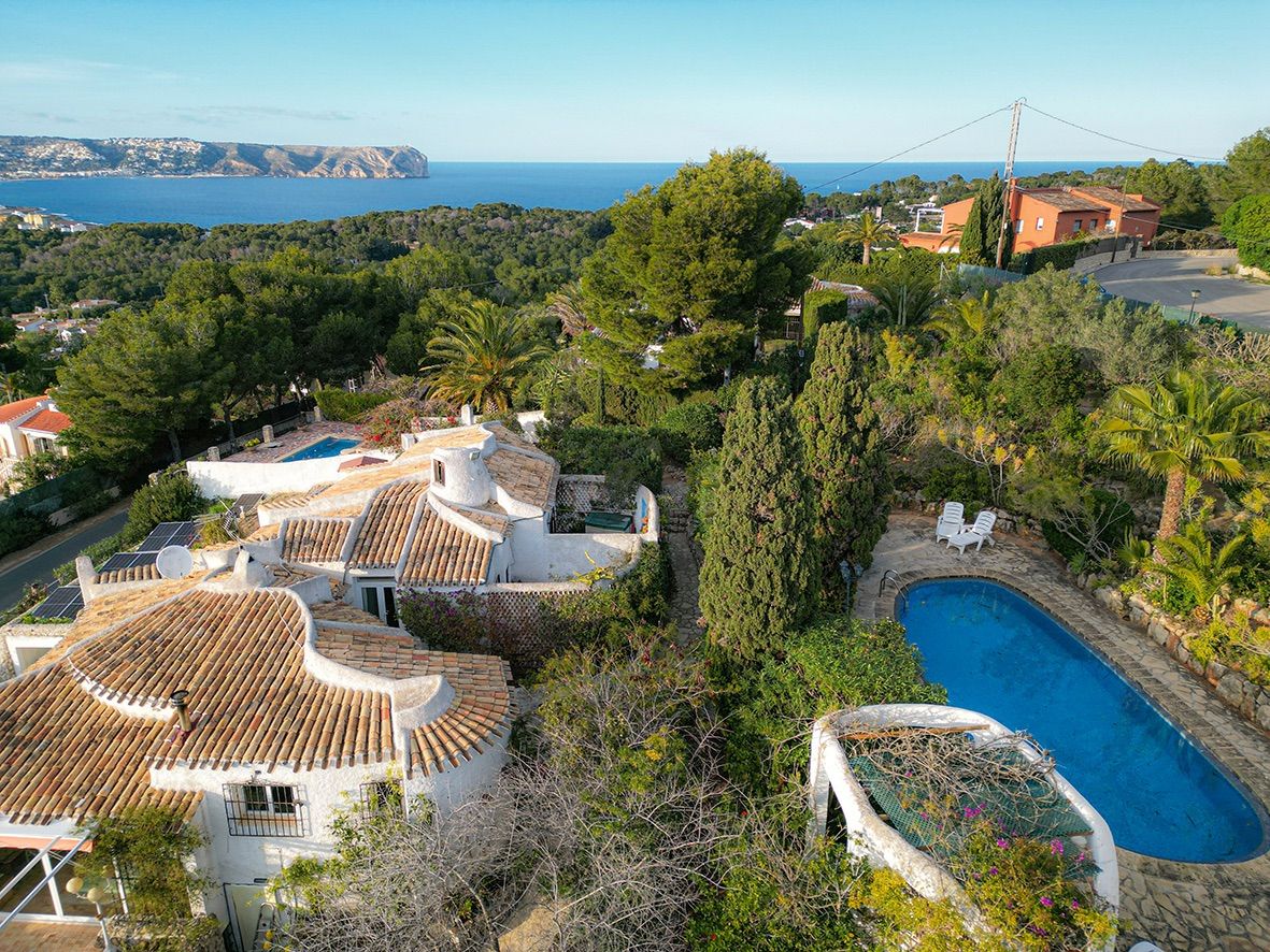 Vista aérea de la villa tradicional con tejados de teja curva, piscina privada y amplias vistas panorámicas al mar Mediterráneo y la costa de Jávea.