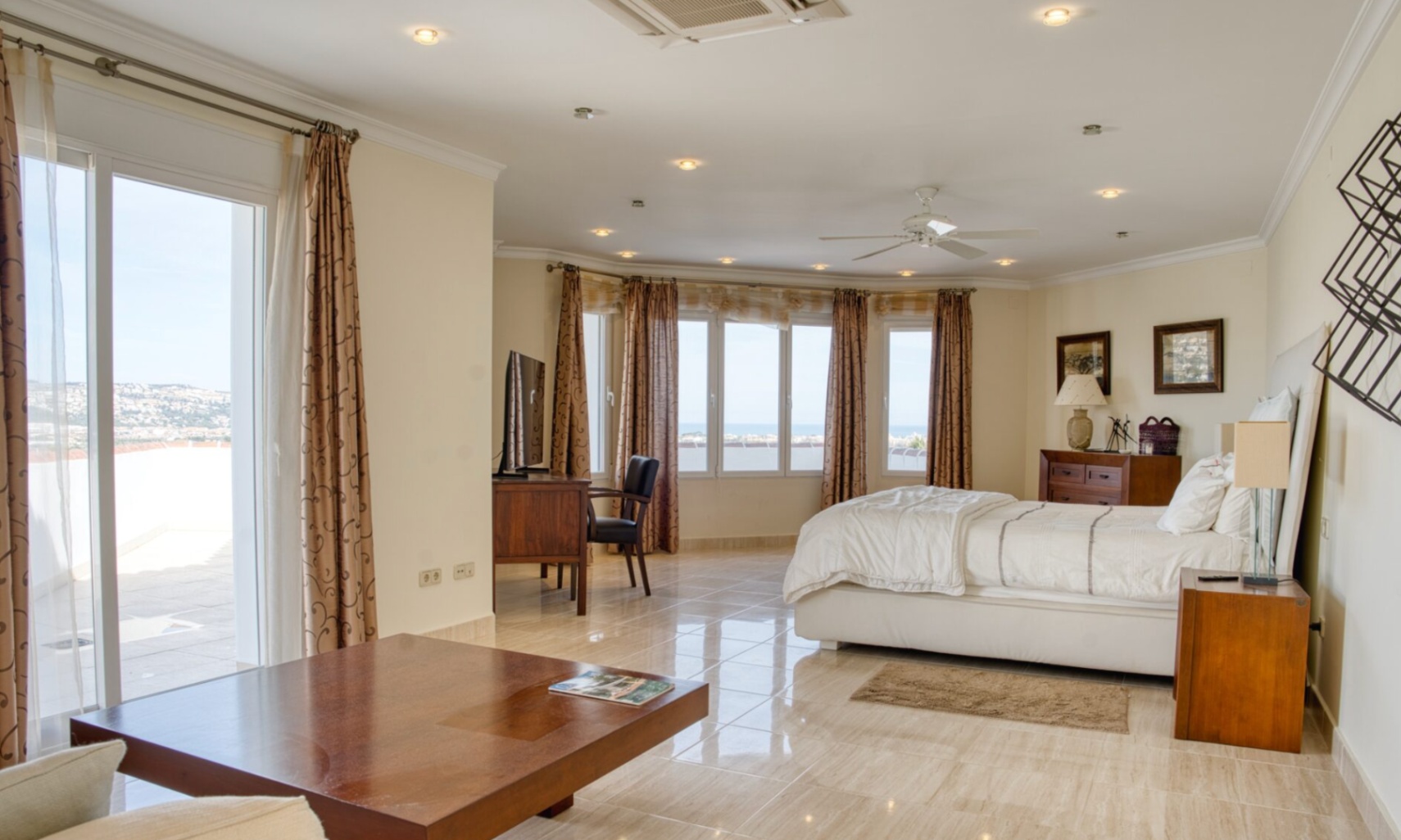 Dormitorio principal con suelos cerámicos, zona de escritorio y amplios ventanales con vistas al mar. Dispone de acceso directo a la terraza privada y luz natural.