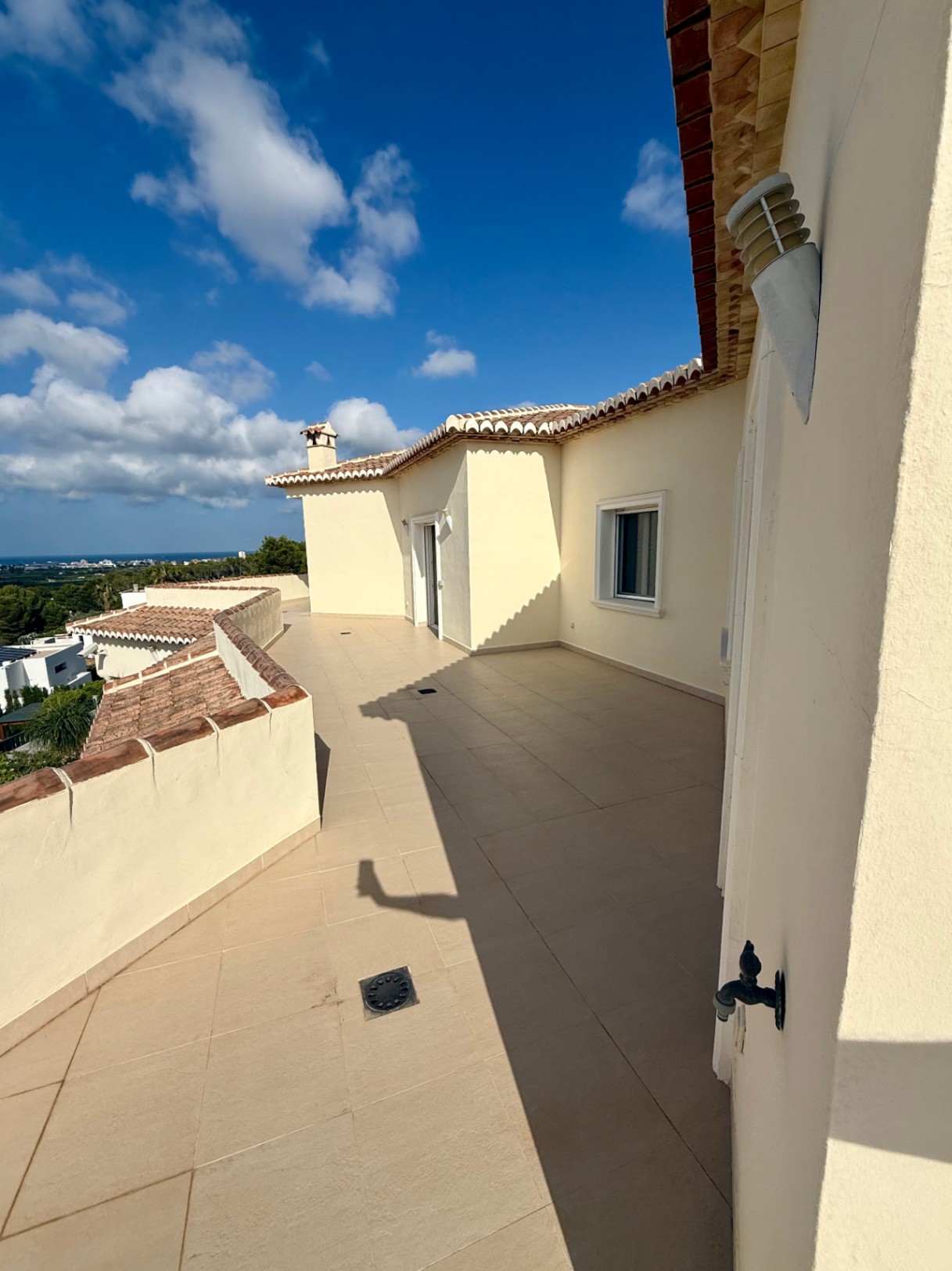 Terraza superior perimetral con suelo de gres cerámico y vistas despejadas al Mediterráneo. Destaca su arquitectura curva y los acabados tradicionales en teja.