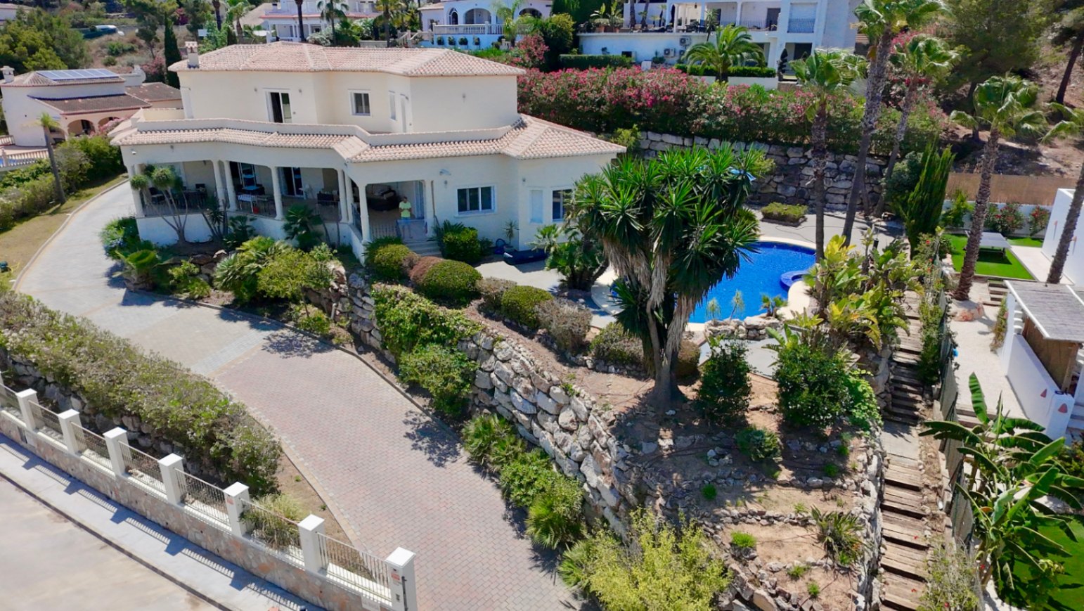 Vista aérea de la villa en Piver, mostrando la arquitectura mediterránea, piscina privada rodeada de palmeras y muros de piedra natural en una parcela elevada.